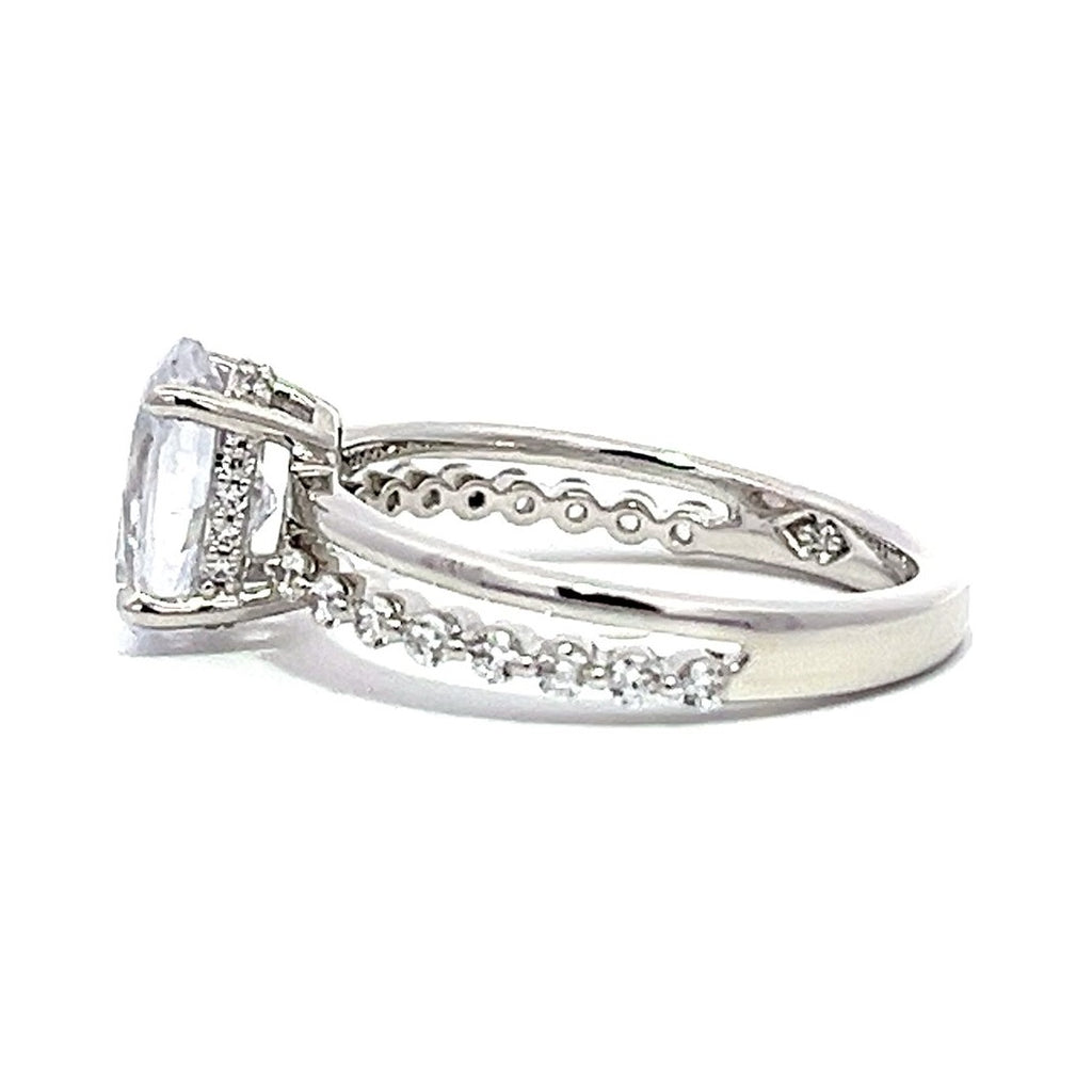 White gold round-shaped diamond engagement ring with a diamond band on a white background.