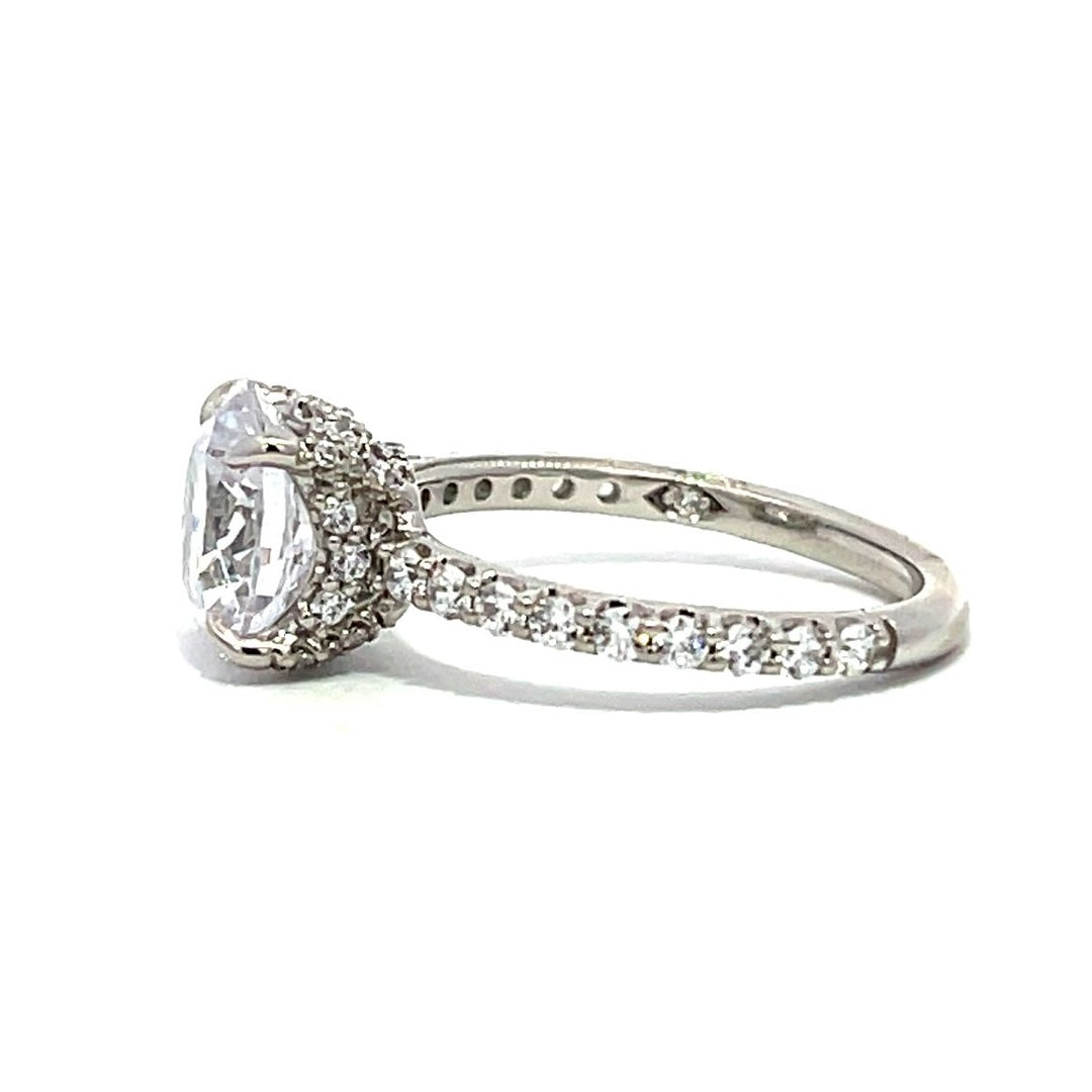 White gold round-shaped diamond engagement ring with a diamond band on a white background.