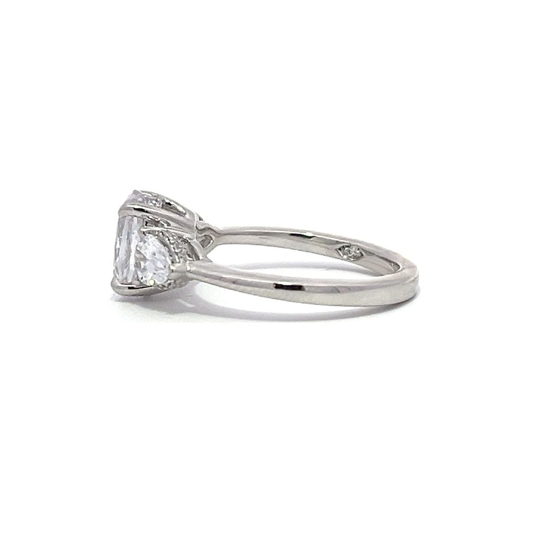 White gold three-stone diamond engagement ring with pear-shaped side stones on a white background.