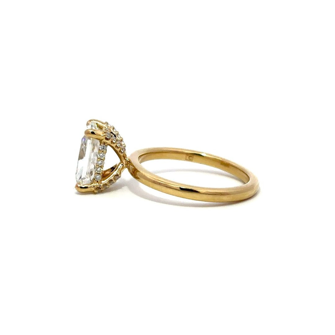 Yellow gold engagement ring with a diamond halo setting on a white background