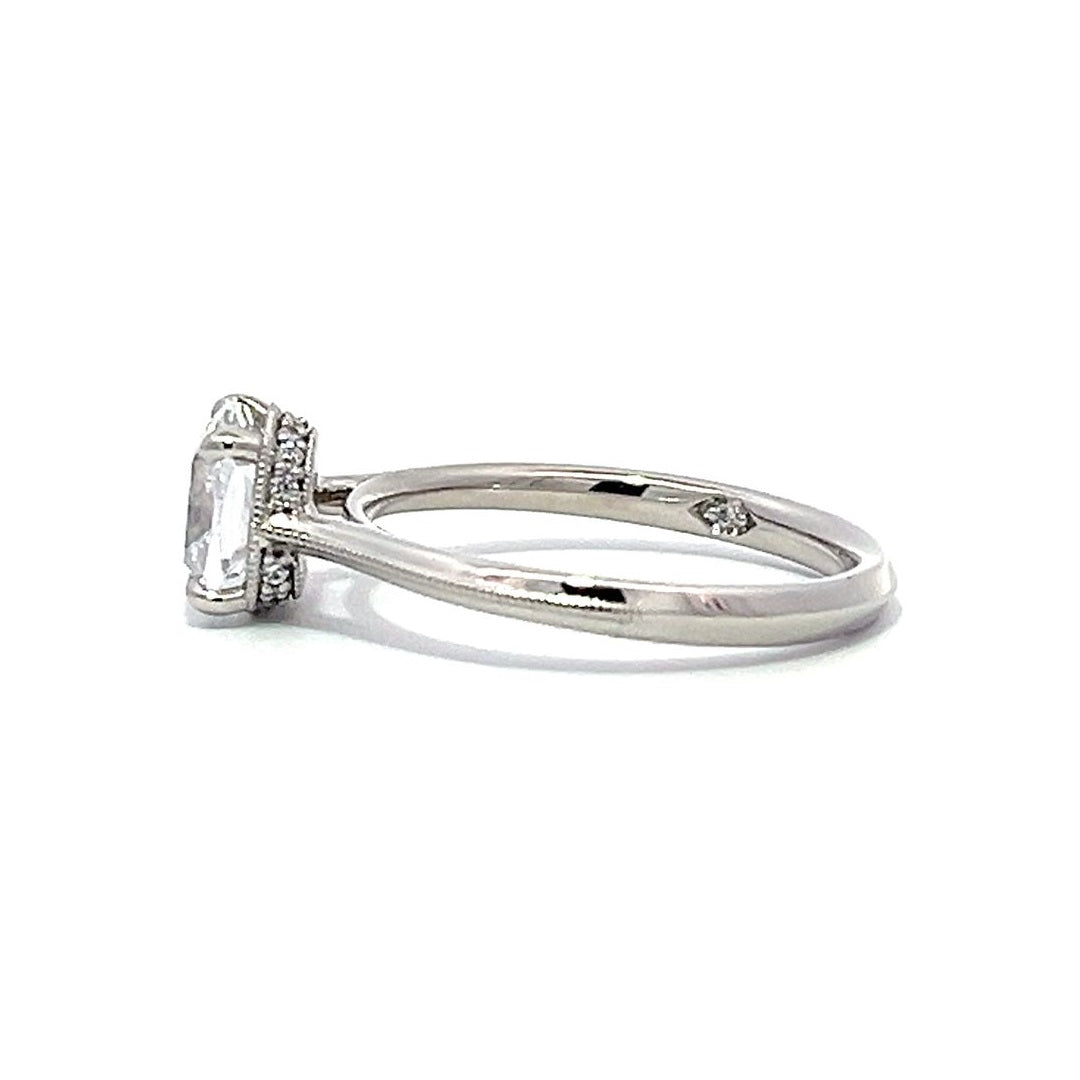 White gold emerald-cut diamond engagement ring with a diamond band on a white background.