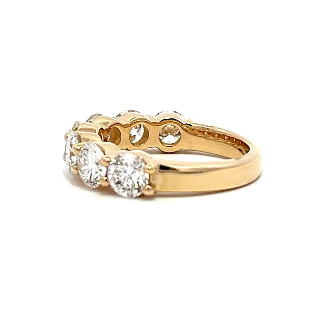 Yellow gold eternity band with round diamonds on a white background