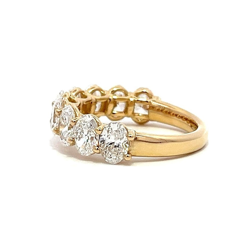 Yellow gold eternity band with oval-shaped diamonds on a white background.