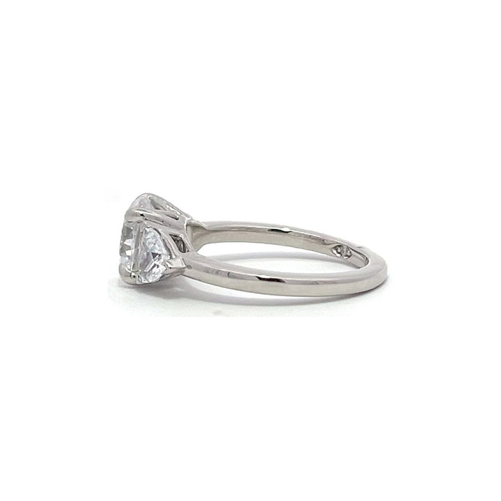 White gold three-stone diamond engagement ring with pear-shaped side stones on a white background