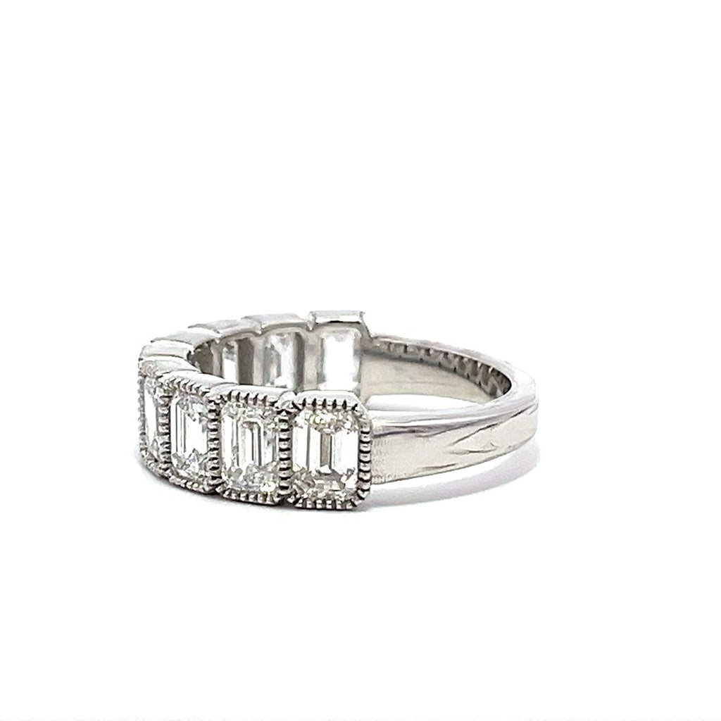 White gold eternity band with bezel-set emerald diamonds on a white background.