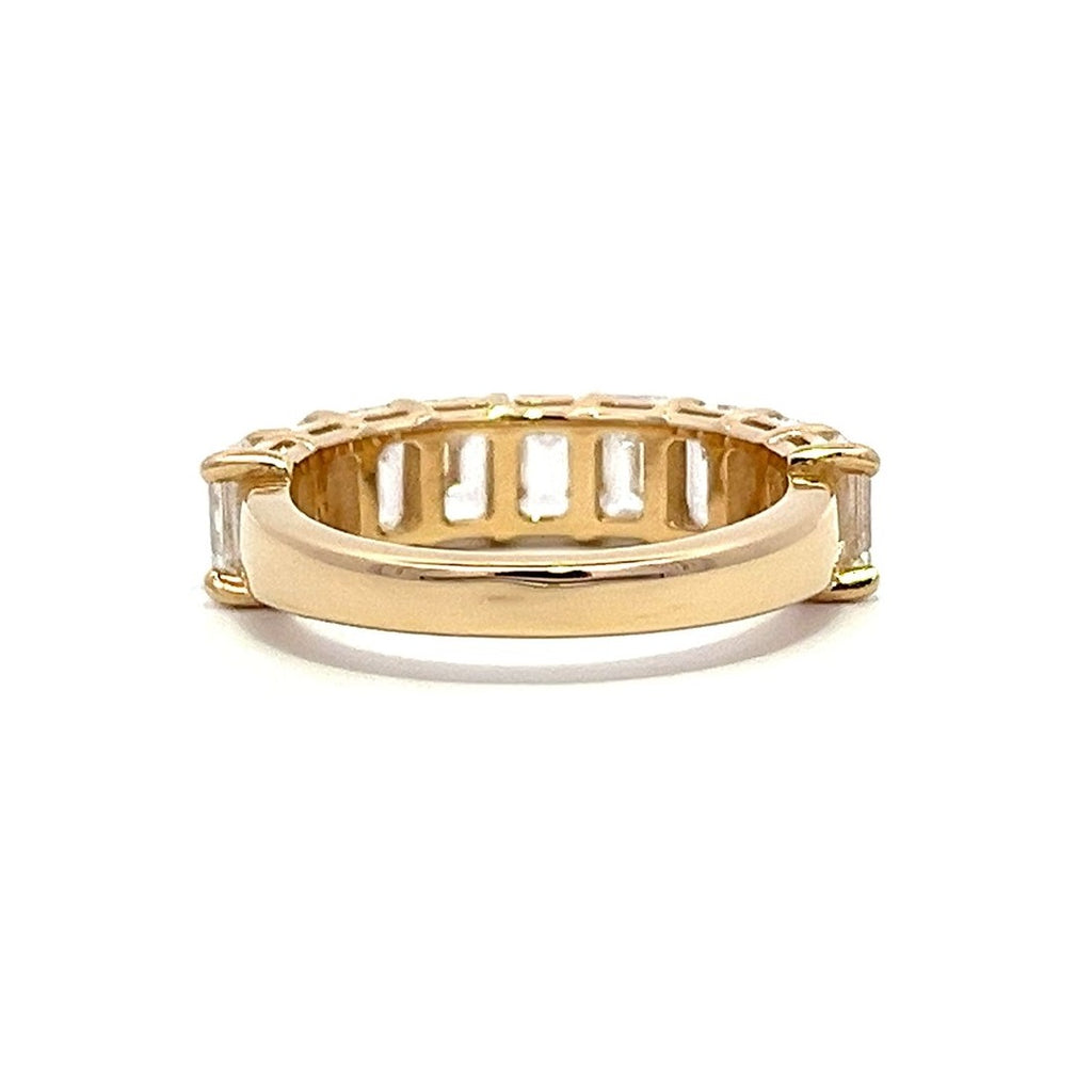 Yellow gold eternity band with emerald-cut diamonds on a white background.