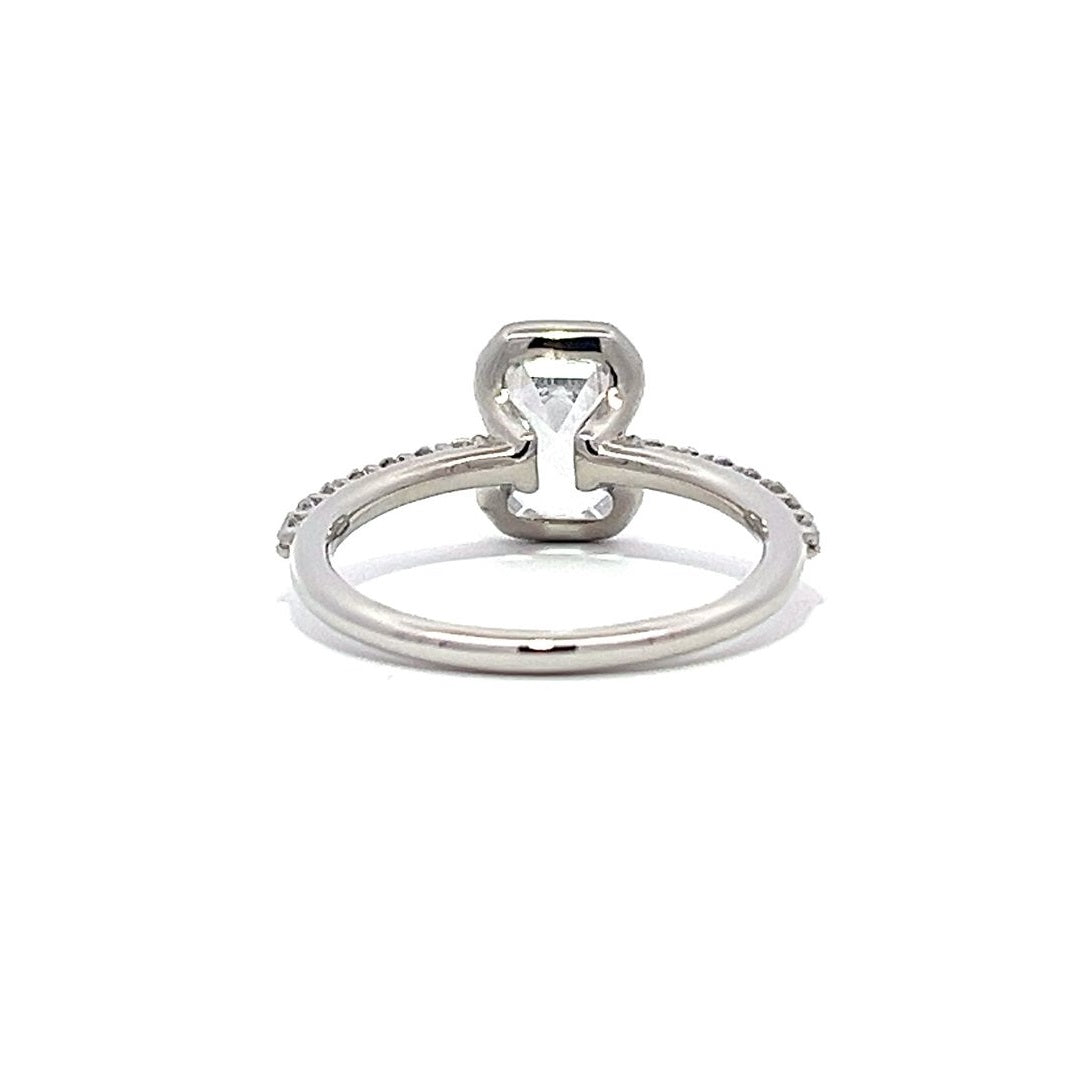 White gold emerald-cut diamond engagement ring with a diamond band on a white background.