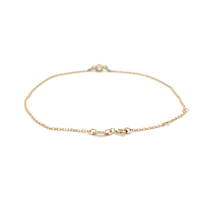 Yellow gold bracelet with a single diamond on a white background.