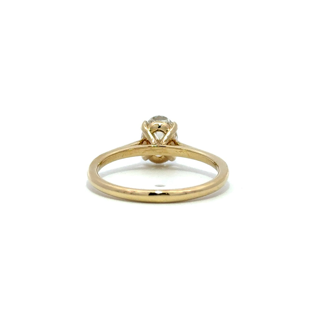 Yellow gold solitaire engagement ring with a oval cut diamond center stone on a white background.