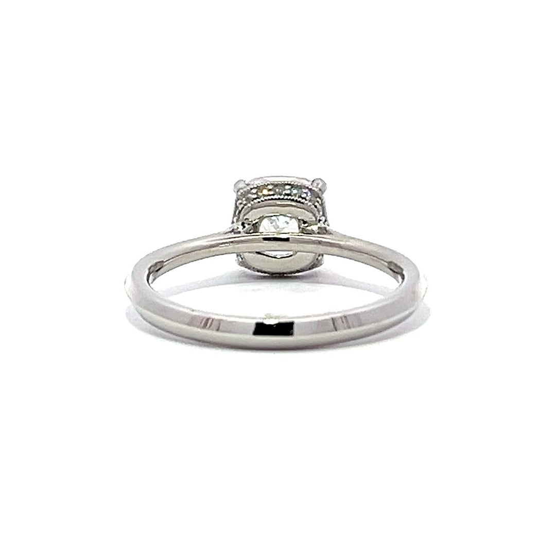 White gold emerald-cut diamond engagement ring with a diamond band on a white background.