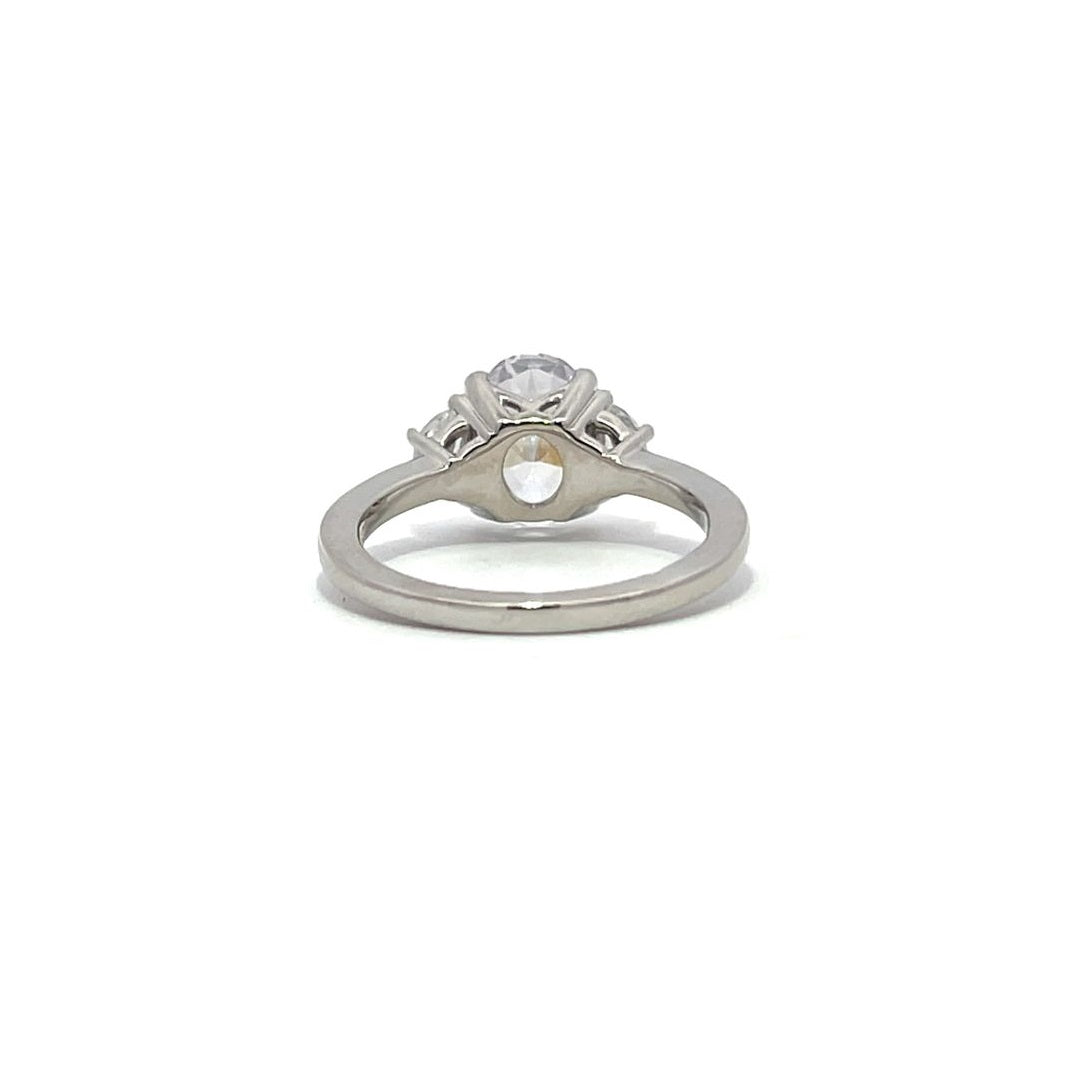 White gold three-stone diamond engagement ring with pear-shaped side stones on a white background.