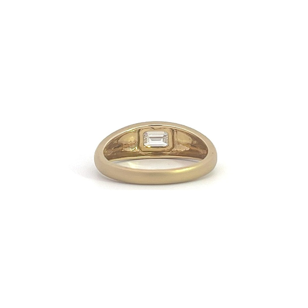 Yellow gold ring with an emerald-cut diamond set in a matte gold band, on a white background.