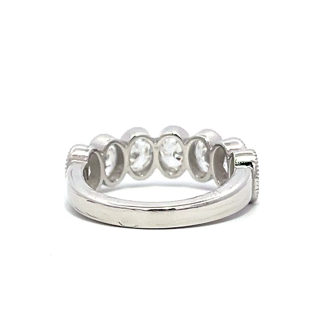 White gold eternity band with bezel-set oval diamonds on a white background.