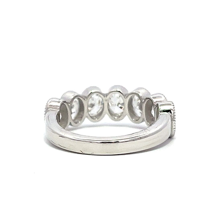 White gold eternity band with bezel-set oval diamonds on a white background.