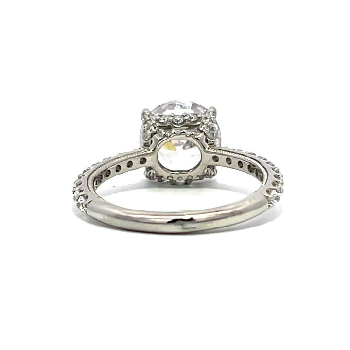 White gold round-shaped diamond engagement ring with a diamond band on a white background.