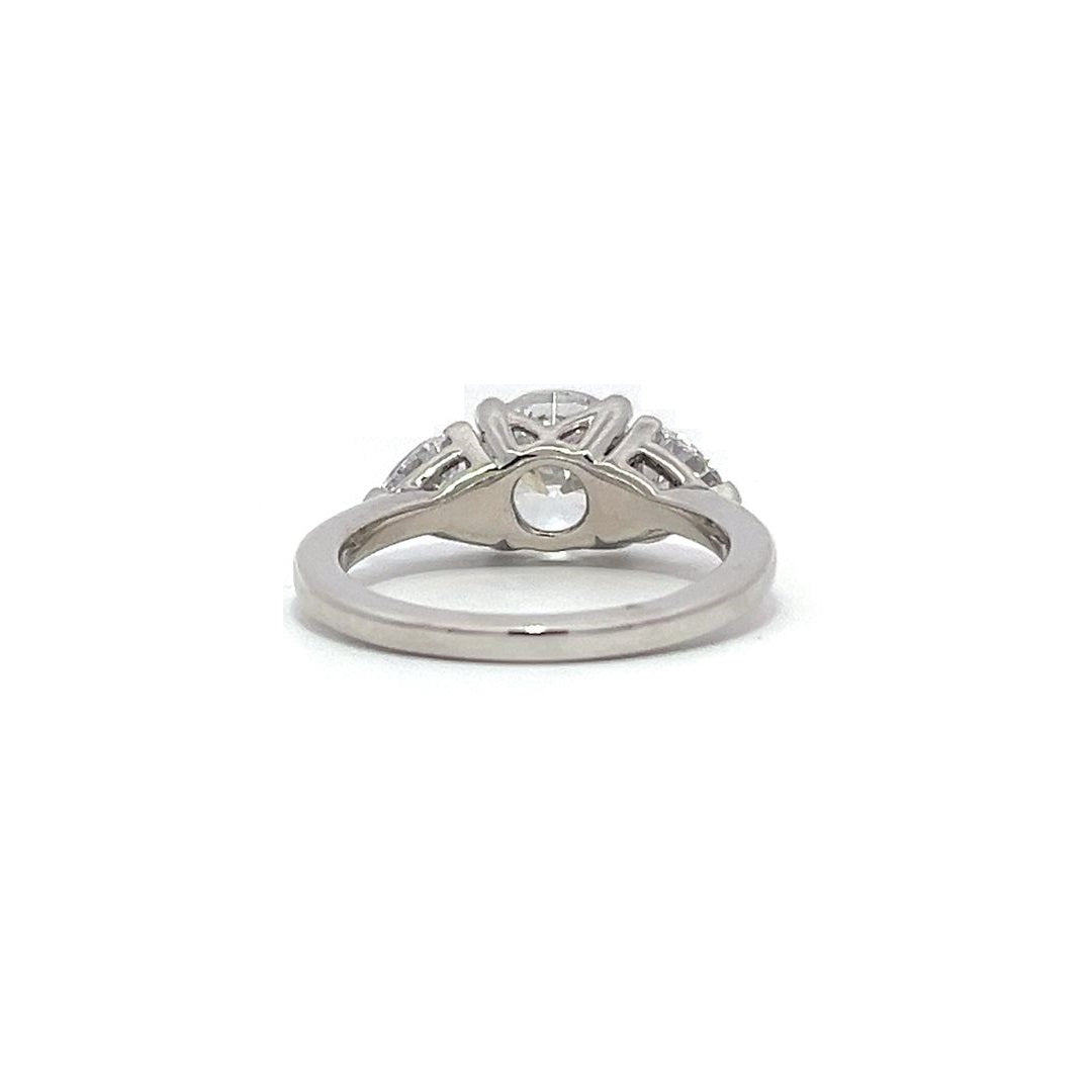 White gold three-stone diamond engagement ring with pear-shaped side stones on a white background