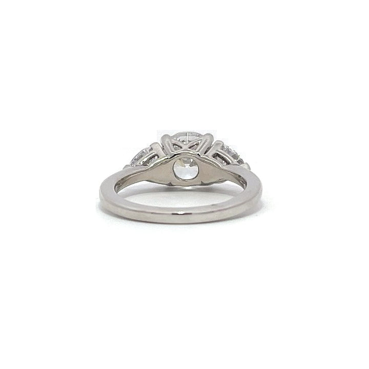 White gold three-stone diamond engagement ring with pear-shaped side stones on a white background