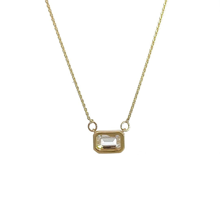 Yellow gold necklace with an emerald-cut diamond pendant on a white background.