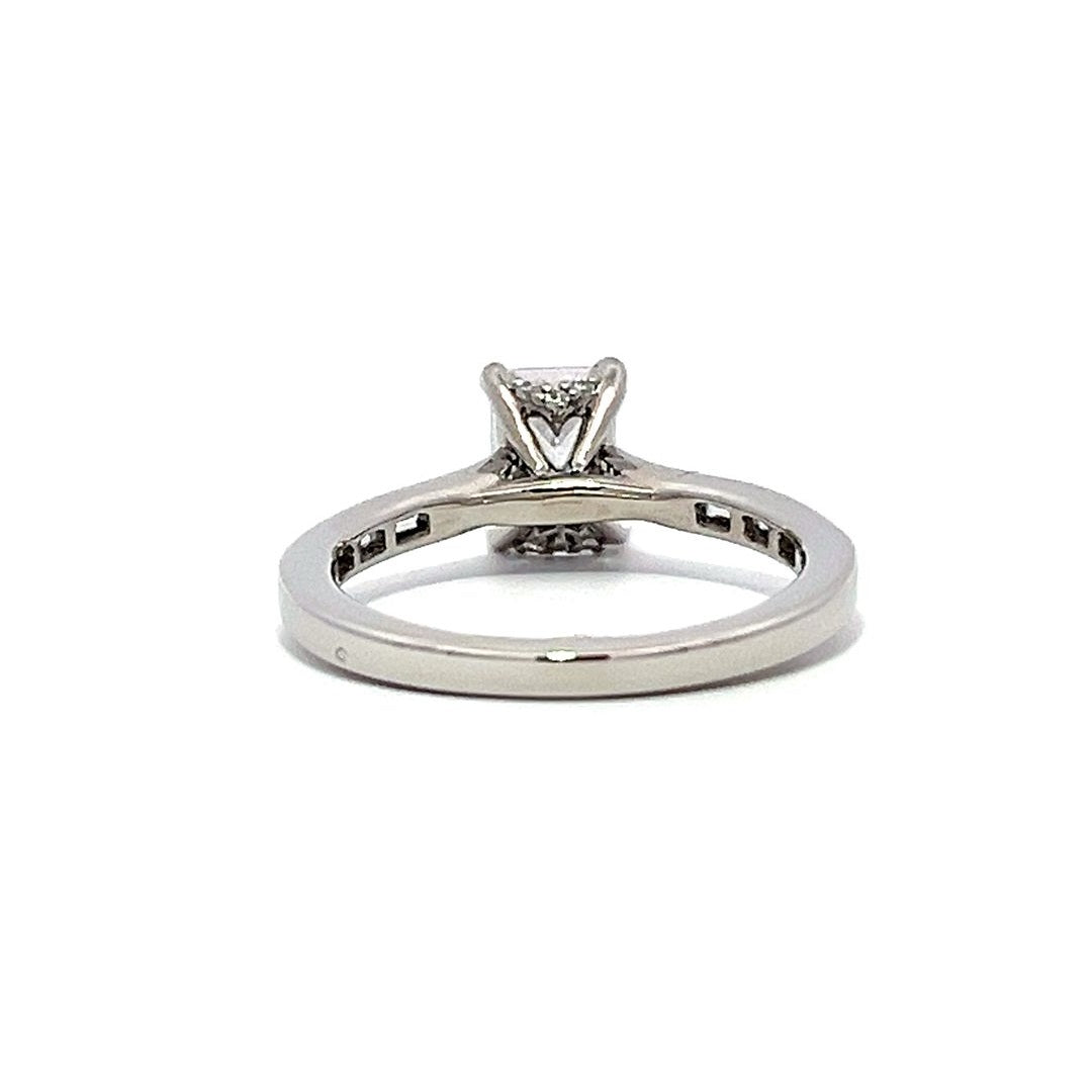 White gold emerald-cut diamond engagement ring with a diamond band on a white background.