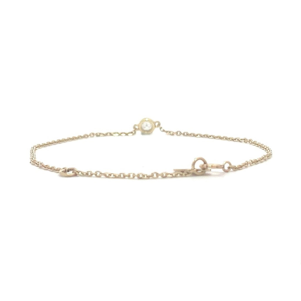 Yellow gold bracelet with a single diamond pendant in a bezel set on a white background.