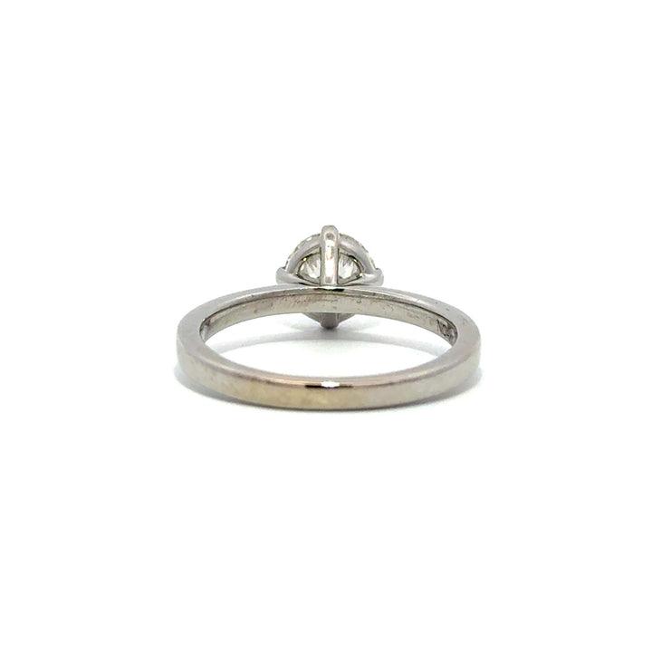 Silver gold solitaire engagement ring with a round cut diamond center stone on a white background.