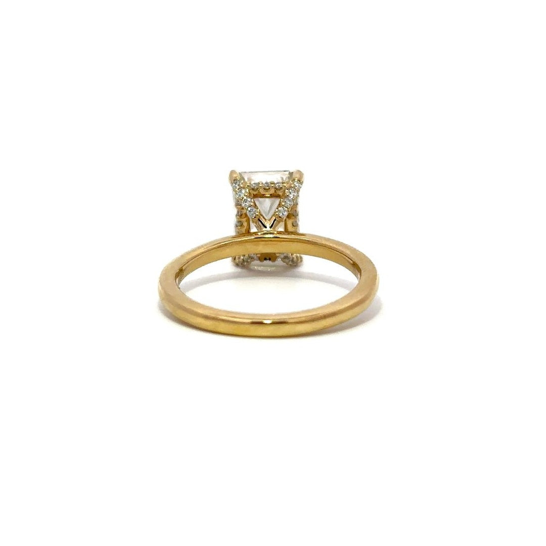 Yellow gold engagement ring with a diamond halo setting on a white background