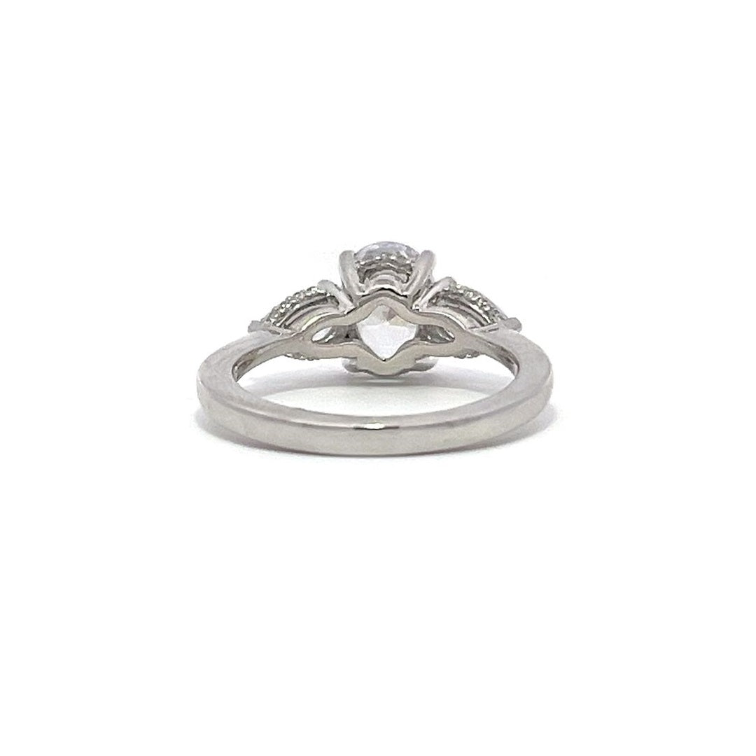 White gold three-stone diamond engagement ring with pear-shaped side stones on a white background.