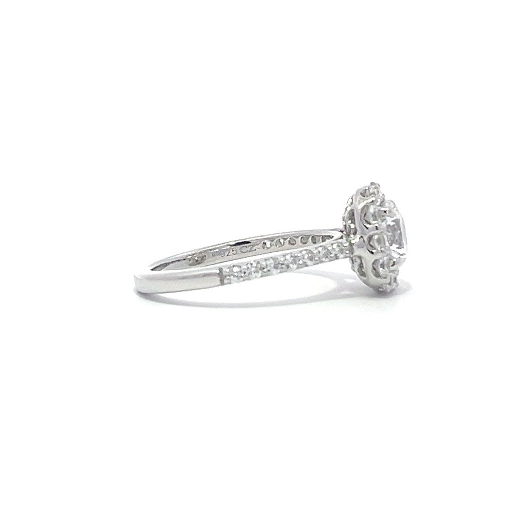 Silver engagement ring with a diamond halo setting and a diamond band on a white background