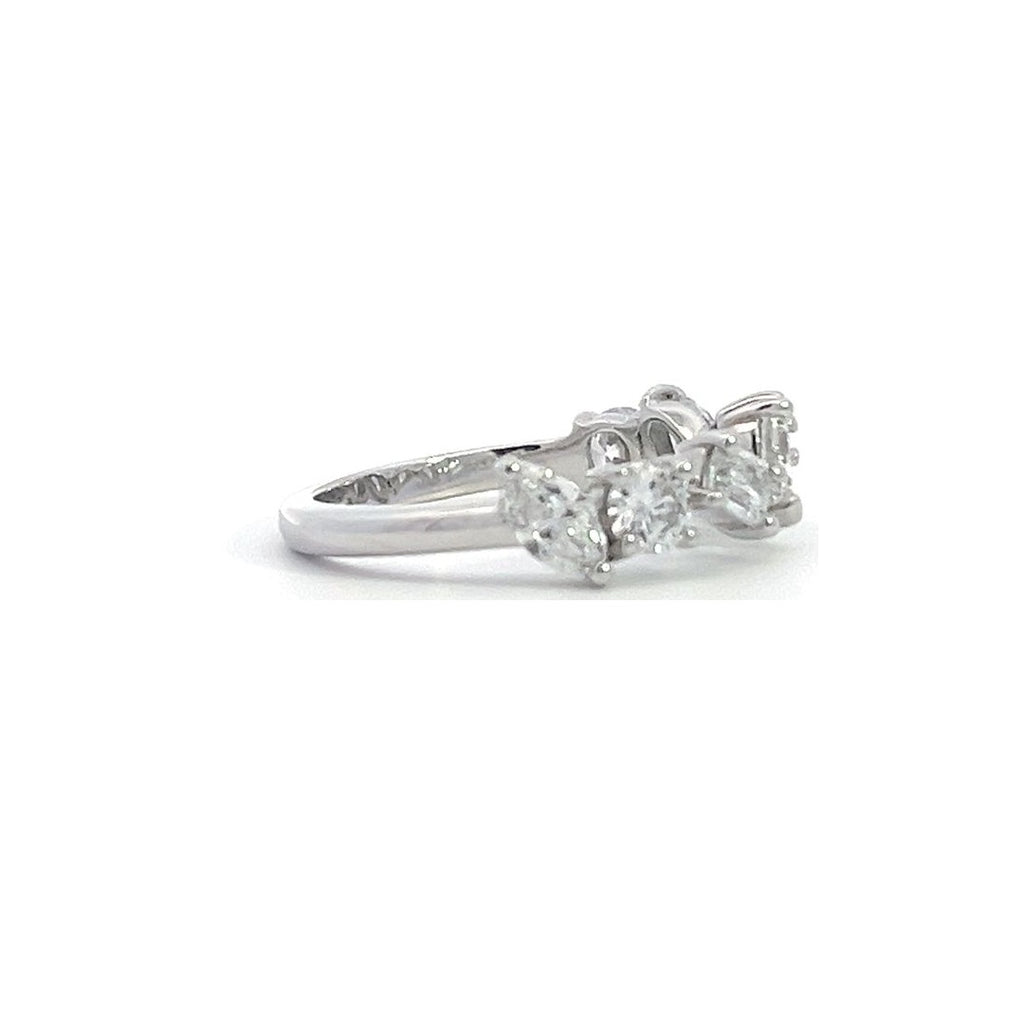 SIlver ring with a row of mixed-cut diamonds, including round, pear, and emerald cuts, on a white background.