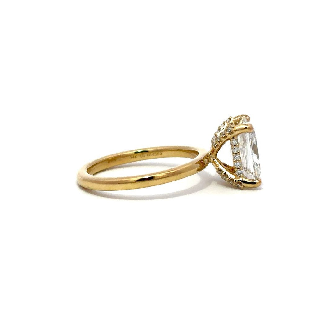 Yellow gold engagement ring with a diamond halo setting on a white background