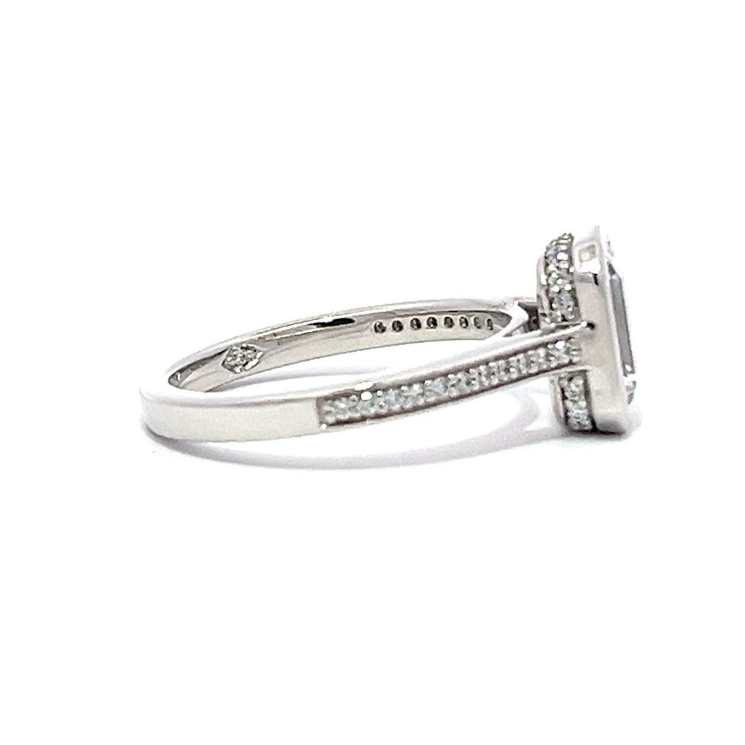 White gold emerald-cut diamond engagement ring with a diamond band on a white background.