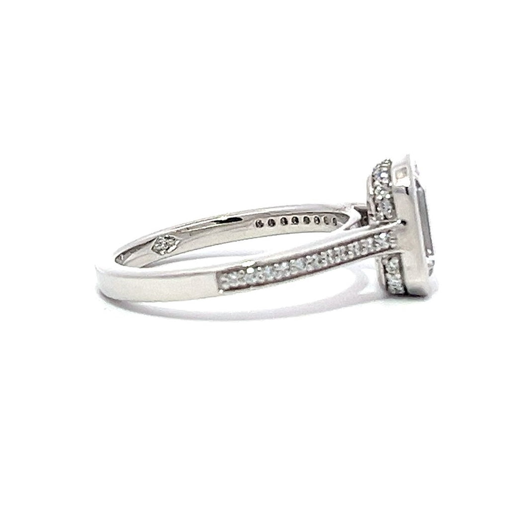 White gold emerald-cut diamond engagement ring with a diamond band on a white background.