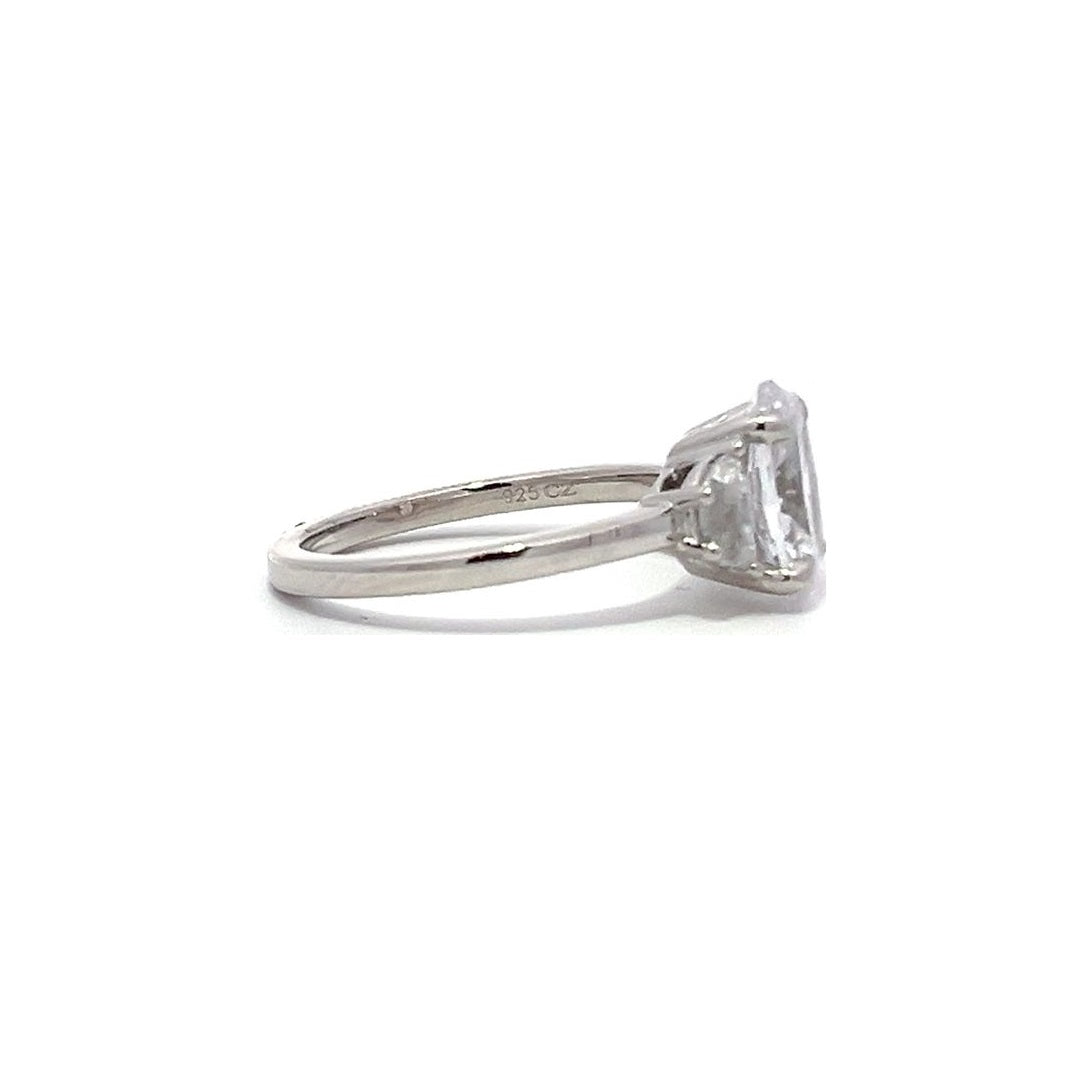 White gold three-stone diamond engagement ring with pear-shaped side stones on a white background.