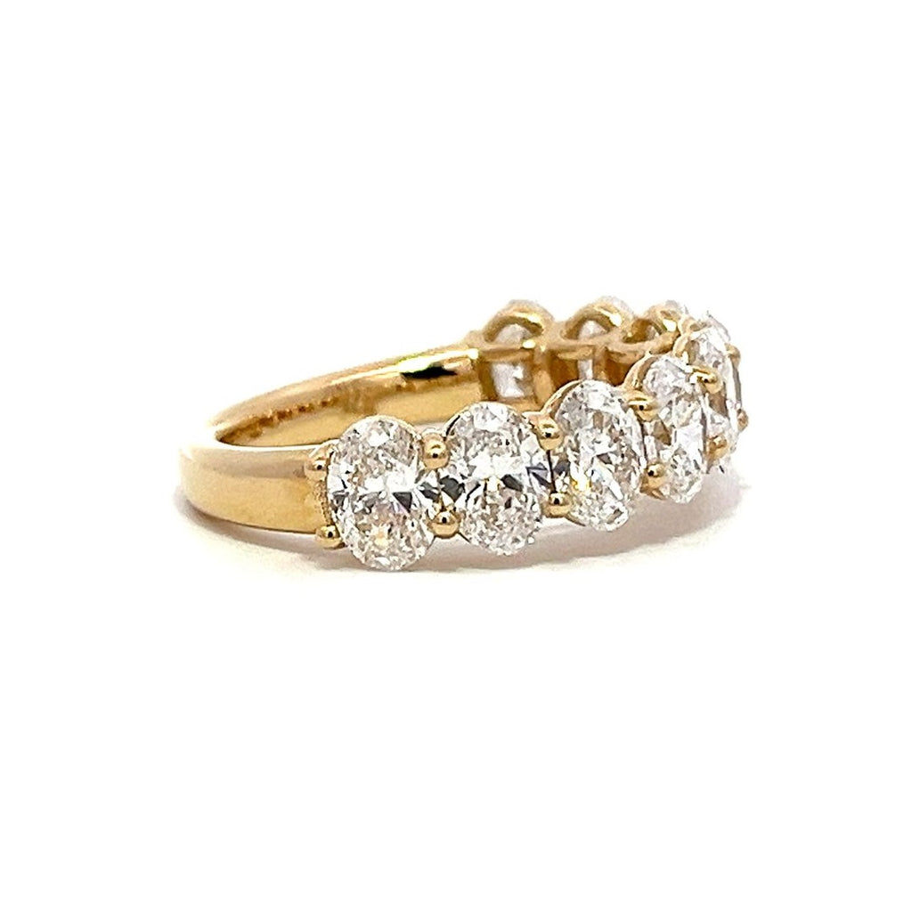 Yellow gold eternity band with oval-shaped diamonds on a white background.