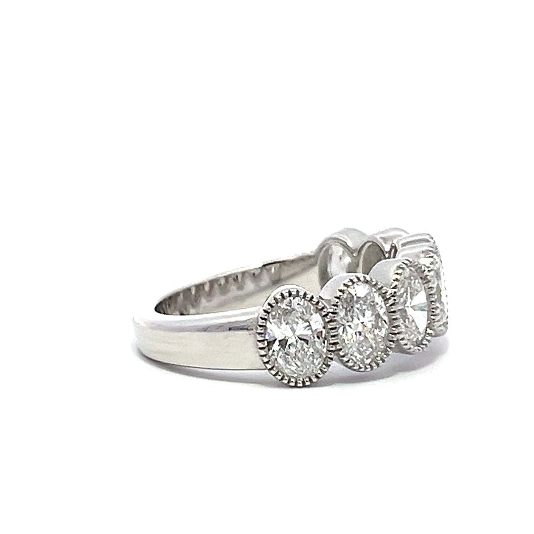 White gold eternity band with bezel-set oval diamonds on a white background.