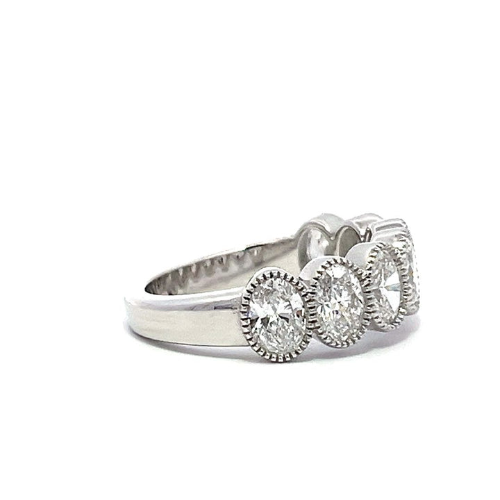 White gold eternity band with bezel-set oval diamonds on a white background.