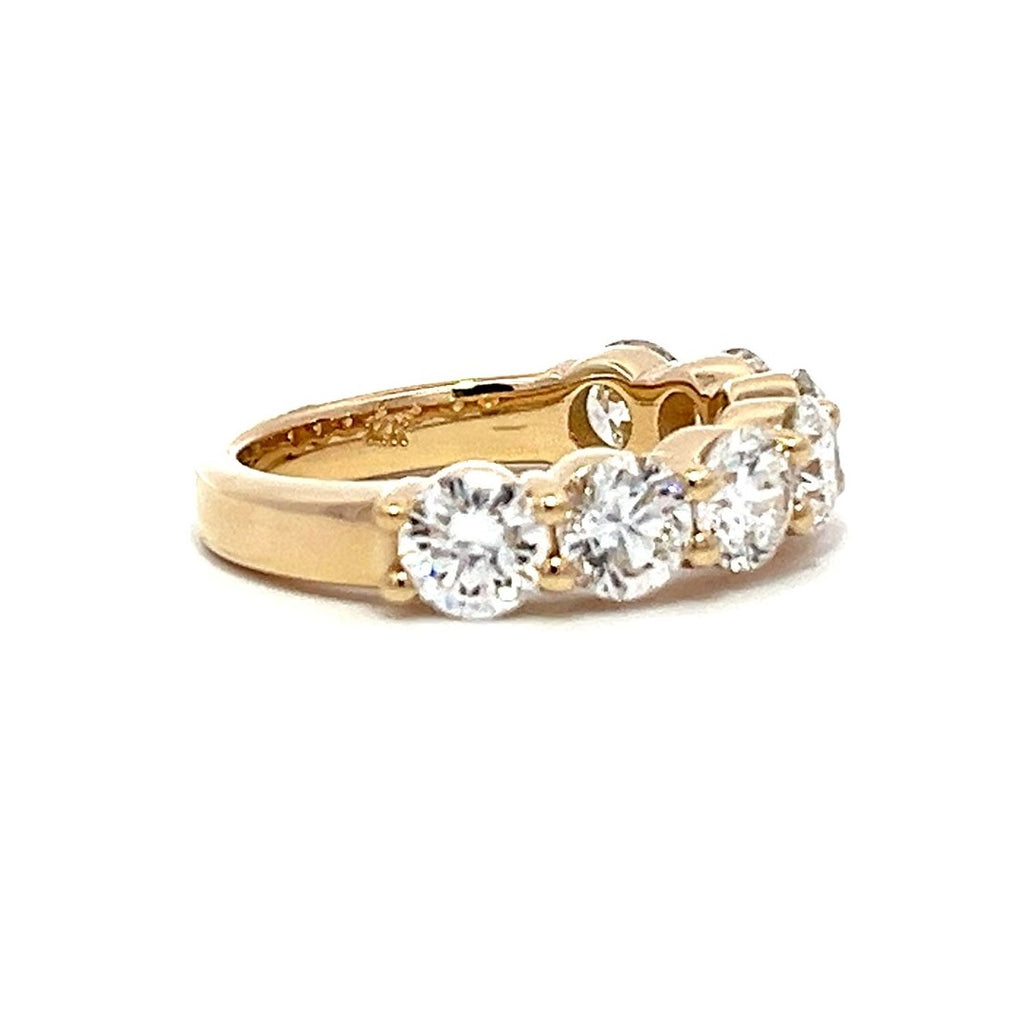 Yellow gold eternity band with round diamonds on a white background