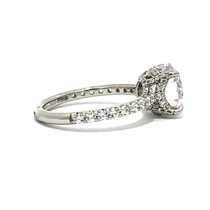 White gold round-shaped diamond engagement ring with a diamond band on a white background.