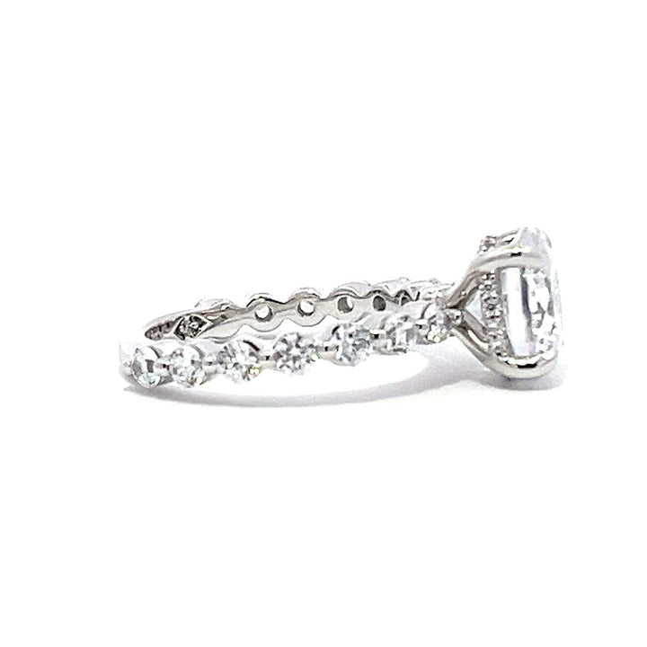 White gold round-shaped diamond engagement ring with a diamond band on a white background.