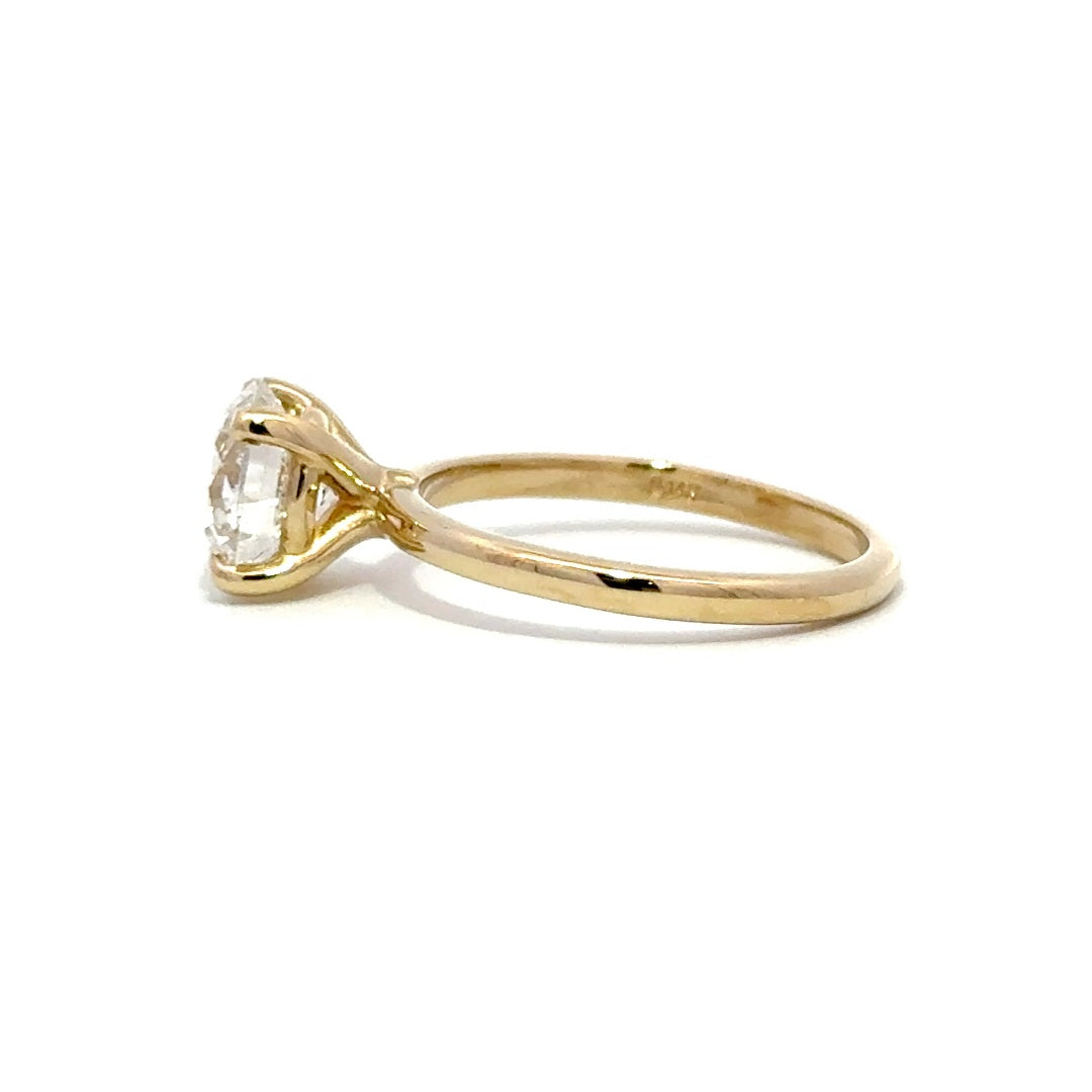 Yellow gold solitaire engagement ring with a round-cut diamond center stone on a white background.