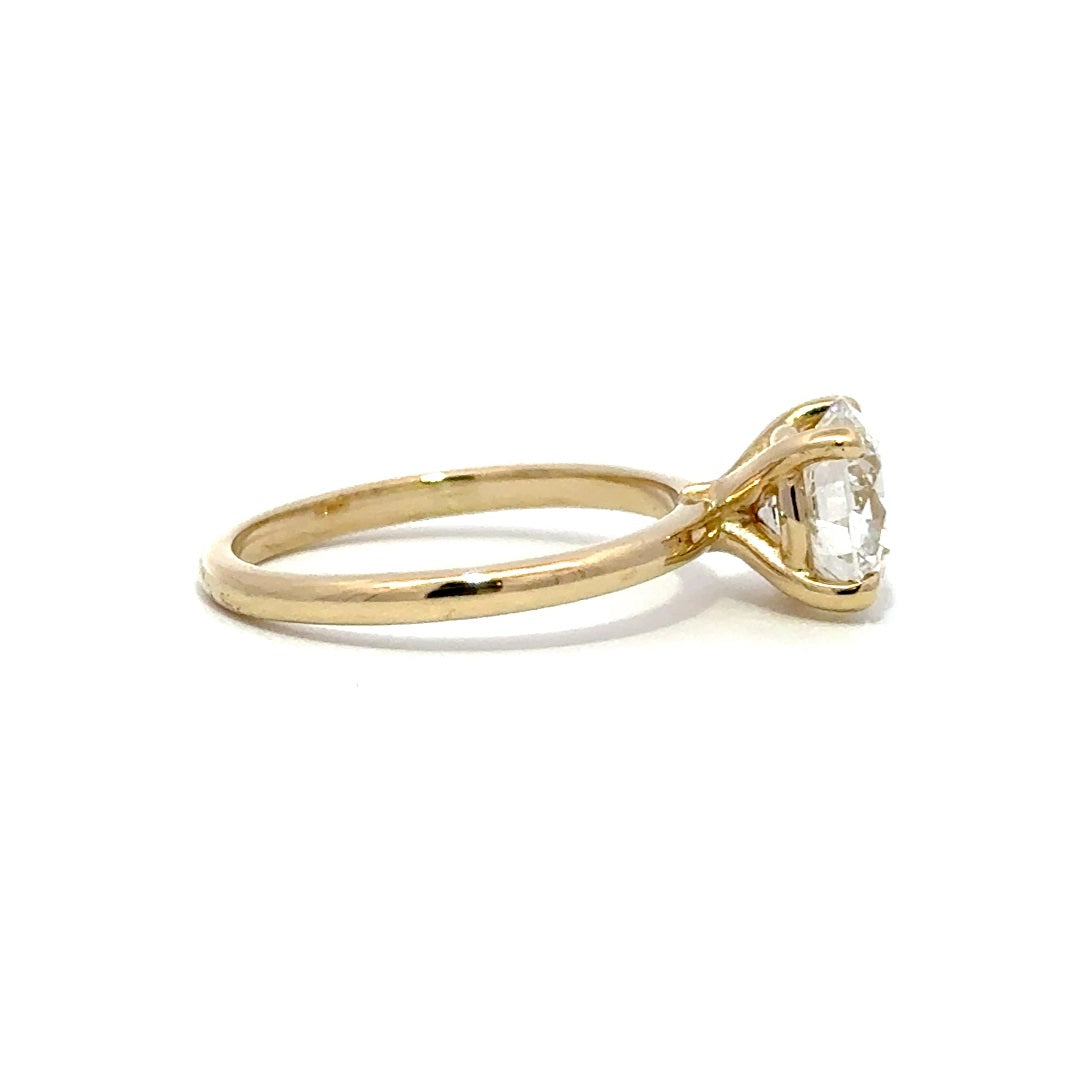 Yellow gold solitaire engagement ring with a round-cut diamond center stone on a white background.