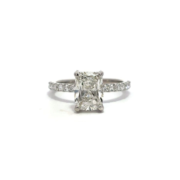 White gold engagement ring with diamond center stone and a diamond-studded band, on a white background.