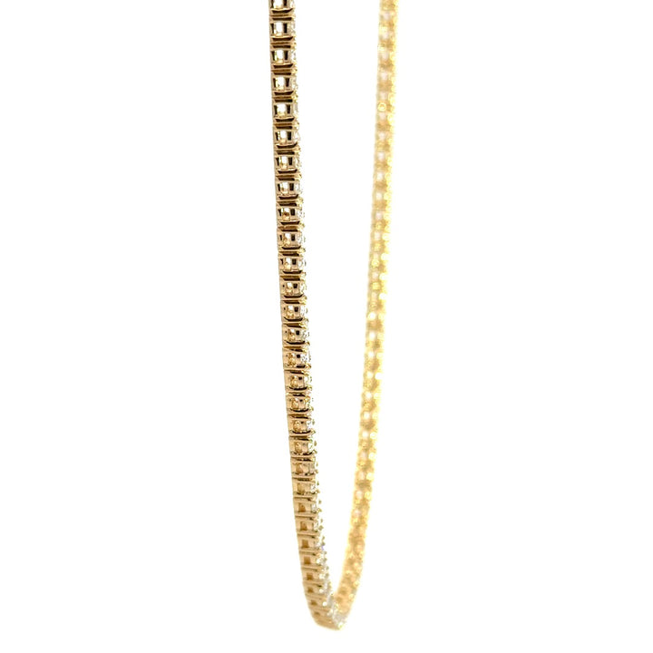 Gold tennis necklace on a white background.