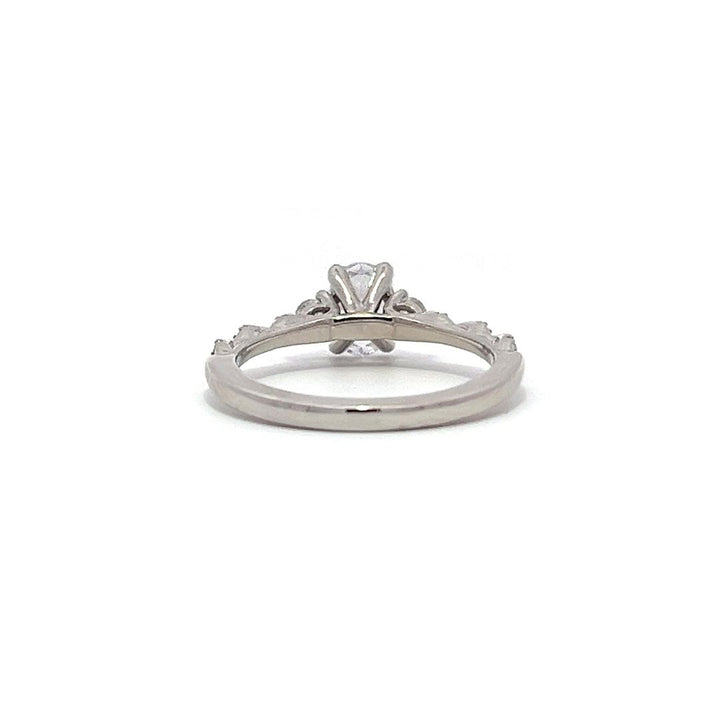 White gold oval diamond engagement ring with side stones and a diamond band on a white background.