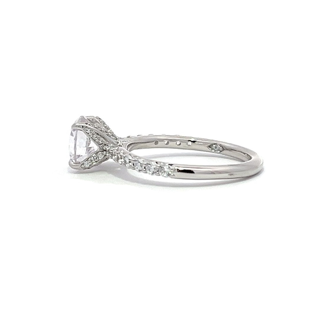 White gold round-shaped diamond engagement ring with a diamond band on a white background.