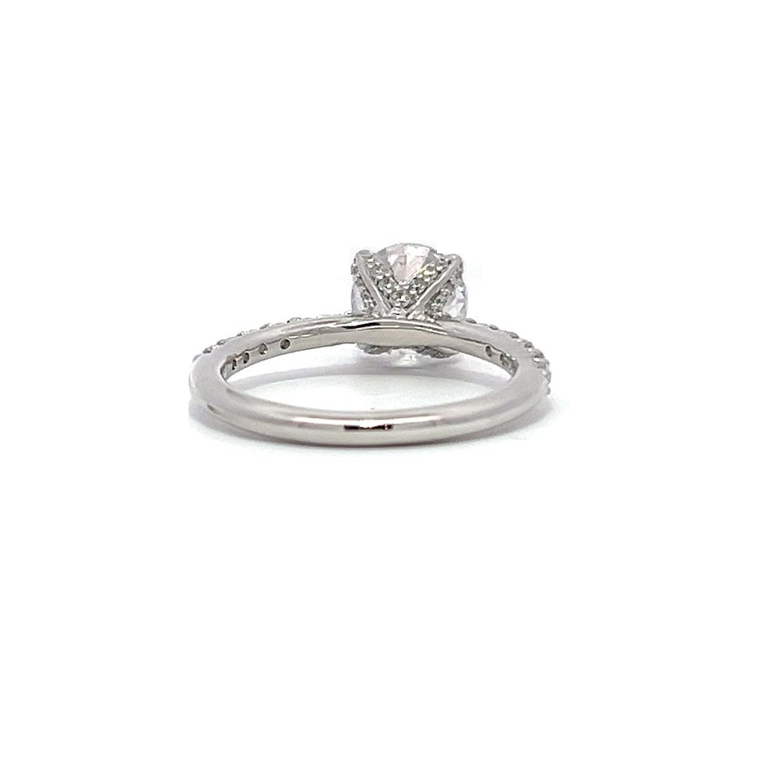 White gold round-shaped diamond engagement ring with a diamond band on a white background.