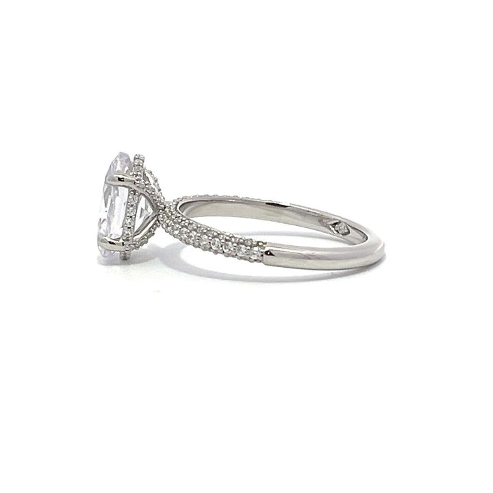 White gold round-shaped diamond engagement ring with a diamond band on a white background.