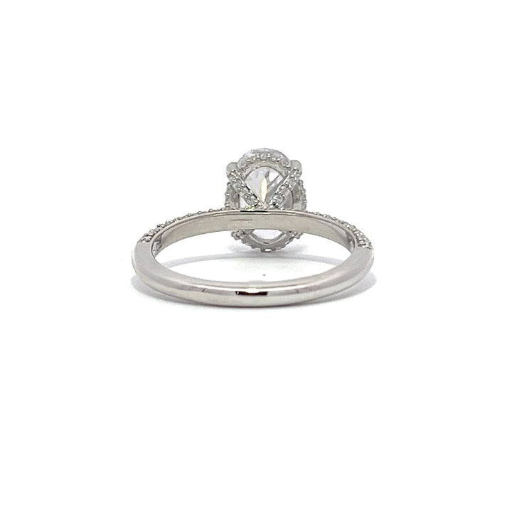 White gold oval-shaped diamond engagement ring with a diamond band on a white background.