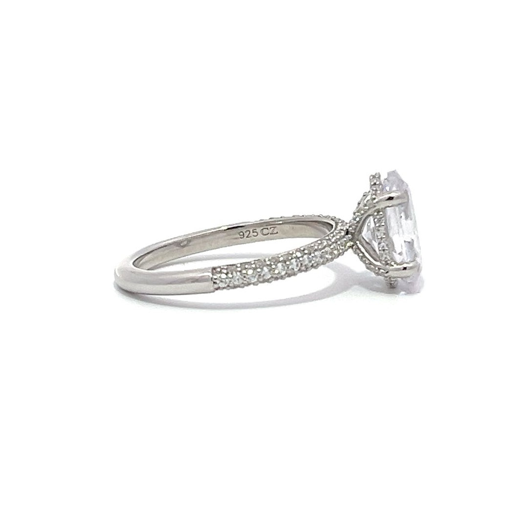 White gold round-shaped diamond engagement ring with a diamond band on a white background.