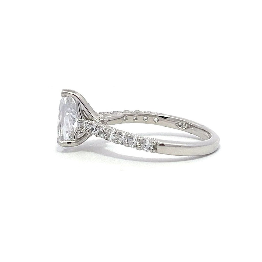 White gold pear-shaped diamond engagement ring with a diamond band on a white background.